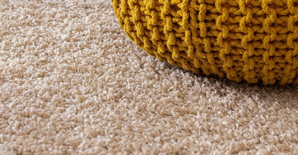 Soft, clean carpet beside a mustard-yellow knitted pouf